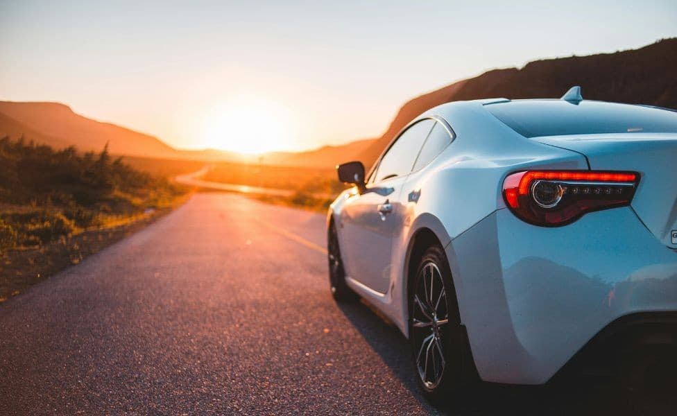 White sports car on open road at sunset on a summer road trip - AutoPartsInformer